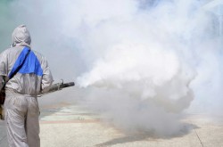 Worker using fogging machine spraying chemical to eliminate mosquitoes and prevent dengue fever